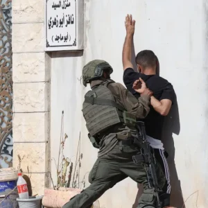 أحد جنود الاحتلال الإسرائيلي يوقف مواطنا فلسطينيا لدى محاولته الوصول إلى منزله في مخيم طولكرم (الأوروبية)
