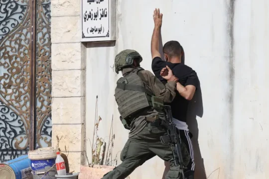 أحد جنود الاحتلال الإسرائيلي يوقف مواطنا فلسطينيا لدى محاولته الوصول إلى منزله في مخيم طولكرم (الأوروبية)