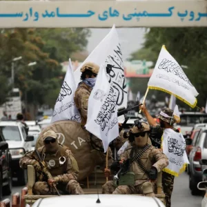 مقاتلون من طالبان يحملون أعلام إمارة أفغانستان الإسلامية في الذكرى الأولى لتحرير كابل في 15 أغسطس/آب 2022 (رويترز)