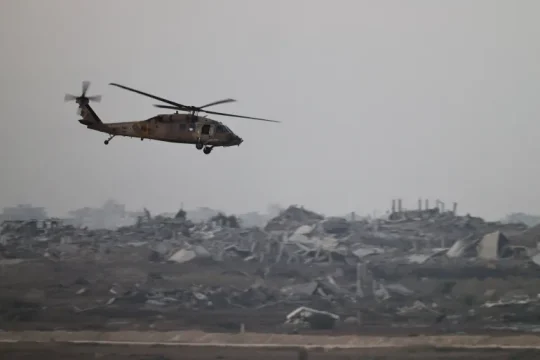 مروحية إسرائيلة تحلق فوق مناطق داخل قطاع غزة المدمر (رويترز)