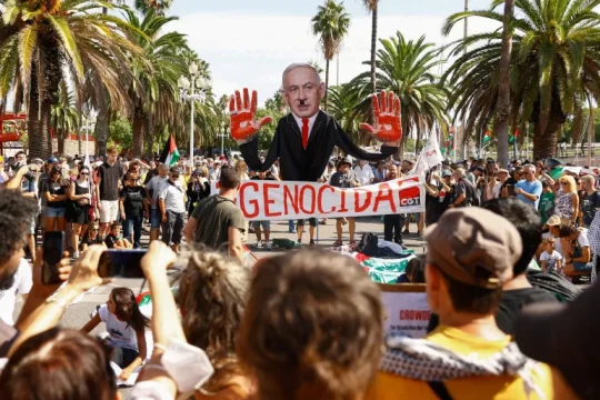 صورة من مظاهرة في إسبانيا لنتنياهو ويداه ملطختان بالدماء في إشارة إلى حرب الإبادة التي يرتكبها جيش الاحتلال في غزة (رويترز)