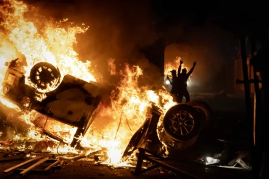 النيران تشتعل في سيارات أمام مقر الشرطة بمدينة يوغياكارتا في إندونيسيا يوم الجمعة (غيتي)